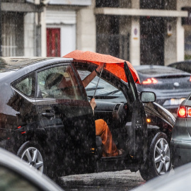 Una se sube a un coche bajo la lluvia, a 3 de julio de 2023, en Valencia, País Valencià.