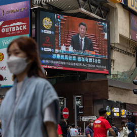 Ciudadanos caminan por una céntrica calle de Hong Kong junto a una pantalla gigante con el presidente de China, Xi Jinping, durante su intervención en el Congreso Nacional del Partido Comunista de China el 22 de octubre de 2022.
