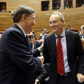 El candidato a la presidencia de la Generalitat, Ximo Puig (d), saluda al presidente de la Generalitat en funciones, Alberto Fabra (d), a su llegada al pleno de Les Corts Valencianes para su investidura