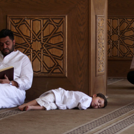 Un hombre lee el Corán mientras un niño se duerme en una mezquita en Siria. REUTERS/Khalil Ashawi