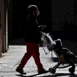 Un hombre pasea con un carrito de bebé por la ciudad de València.