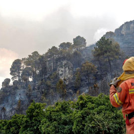Una bombera observa el frente del incendio forestal en la localidad de la Barraca de Aguas Vivas (Valencia). Cuatro incendios forestales afectan a una decena de municipios en Valencia, el más preocupante en Carcaixent, donde han sido evacua