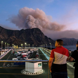 Dos personas observan al caer la tarde la columna de humo reactivada en el Pinar de Tamadaba que se ve desde el muelle de Agaete. EFE/Ángel Medina G.