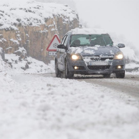 Un coche circula por la CV15 en el Coll d'Ares cuando la nieve ha cubierto el interior de la provincia de Castellón. /EFE
