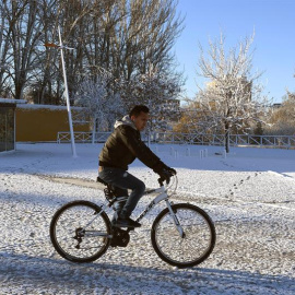 Un hombre se desplaza en bicicleta en medio del temporal de frío y nieve que afecta a León. / EFE