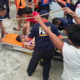 Un pasajero rescatado es llevado a una ambulancia al llegar al puerto de Ormoc./ AFP