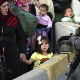 Una niña palestina mira al soldado israelí que revisa las identificaciones de las mujeres palestinas que quieren cruzar el paso de control de Belén, al sur de Jerusalén. EFE
