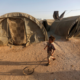 Un niño sirio refugiado juega con una rueda en el campo de Jrzinaz, en la parte sur de Idlib, Siria. REUTERS / Khalil Ashawi