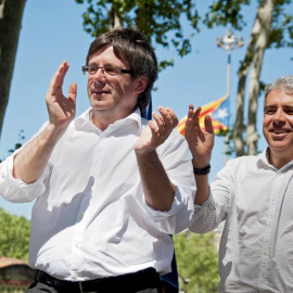 El cabeza de lista de CDC, Francesc Homs (d), y el presidente de la Generalitat, Carles Puigdemont (i), saludan a los asistentes tras la comida celebrada con motivo del acto de final de campaña de CDC en Girona celebrado en el Parc de la De