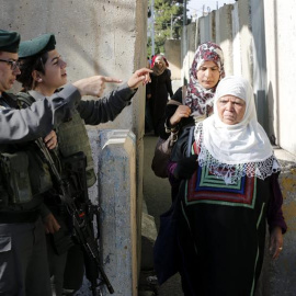 Miembros de la seguridad israelí chequean a unas mujeres musulmanas mientras cruzan la zona de control de Israel a las afueras de la ciudad cisjordana de Belén. - EFE