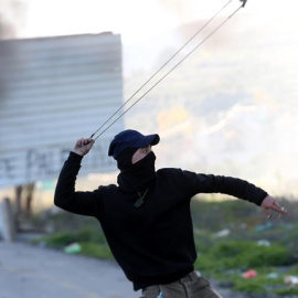 Un palestino utiliza su honda para lanzar piedras durante una protesta en el cruce de Huwara, cerca de Nablus, Cijsordania, hoy, 14 de diciembre de 2018. Cinco palestinos resultaron heridos durante las protestas, según informaciones. EFE/ A
