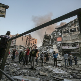 Un grupo de palestinos inspeccionan los restos de una torre destruida por un bombardeo israelí.