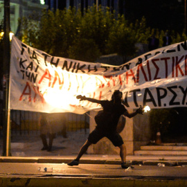Un manifestante lanza un cóctel molotov hacia los antidisturbios durante los enfrentamientos frente al Parlamento griego en Atenas anoche, el 15 de julio de 2015. AFP PHOTO / ANDREAS SOLARO