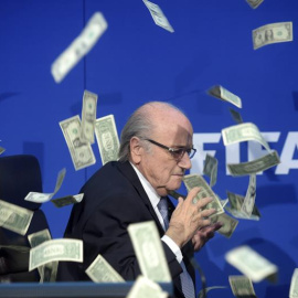 El presidente de la FIFA, Joseph Blatter, bajo una lluvia de billetes que le lanzó el humorista británico Simon Brockin.- ENNIO LEANZA (EFE)