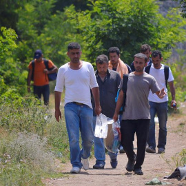 Varias personas caminan junto a un refugio temporal serbio en la frontera con Hungría. / EDVARD MOLNAR (EFE)