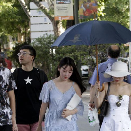 Unas turistas tratan de protegerse del sol con sombreros, paraguas y sombrillas en las cercanias del Museo del Prado en Madrid. /EFE