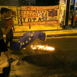 An anti-austerity demonstrator throws a European Union flag into a fire in front of the parliament in Athens, Greece July 22, 2015. Greek Prime Minister Alexis Tsipras sought on Wednesday to contain a rebellion in his left-wing Syriza party