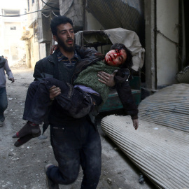 Un joven traslada a un niño herid por los bombardeos en la ciudad siria de Guta, cerca de Damasco. REUTERS/Bassam Khabieh