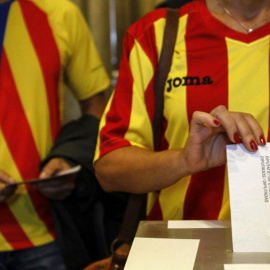 Una ciudadana deposita su voto en una mesa de en un colegio electoral de Barcelona durante el referéndum que tuvo lugar el 9-N del año 2014.- EFE