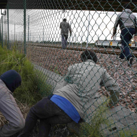 Inmigrantes cruzan una valla al tratar de llegar al tren que los conduce a Inglaterra . REUTERS/Pascal Rossignol