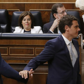 El presidente de Ciudadanos, Albert Rivera (d), pasa por delante de los escaños del presidente del Gobierno en funciones, Mariano Rajoy (detrás-d), y la vicepresidenta en funciones, Soraya Sáenz de Santamaría, en la constitución del Congres