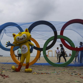 Vinicius, la mascota de los Juegos de Río, posa junto a la escultura de los anillos olímpicos. - EFE