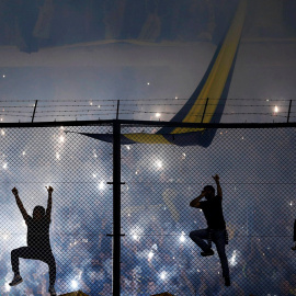 Hinchas del Boca Junios suben a la verja mientras animan a su equipo antes del partido de la Copa Libertadores frente al River Plate, en Buenos Aires.- MARCOS BRINDICCI (REUTERS)