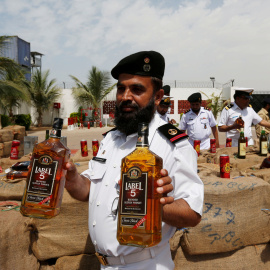 Un oficial de la Agencia de Seguridad Marítima de Pakistán (PMSA) sostiene dos botellas de alcohol durante la demostración de botellas de licor en Karachi, Pakistán. REUTERS/Akhtar Soomro