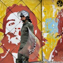 Un policía antidisturbios camina delante de una pared con un mural que representa a Ernesto 'Che' Guevara durante una manifestación de miles por la educación pública en Bogotá, Colombia. GUILLERMO LEGARIA / AFP