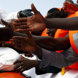 Un grupo de inmigrantes extiende la mano a la espera de ser rescatados frente a la costa de Libia. REUTERS/Darrin Zammit Lupi