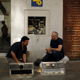 Fos operarios reparan un cajero automático en un banco en Ronda (Málaga). REUTERS/Jon Nazca