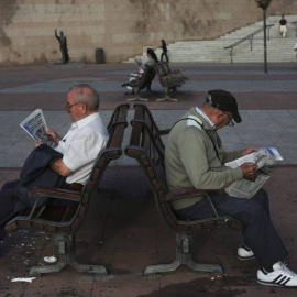 Dos pensionistas leen el periódico en un banco en Madrid. REUTERS