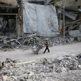 Un hombre empuja un carro por los edificios dañados en la ciudad sitiada de Duma, Guta Oriental, Damasco. REUTERS / Bassam Khabieh