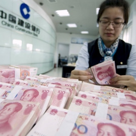 Una cajera del banco chino CCB cuenta billetes de yuan. REUTERS/China Daily