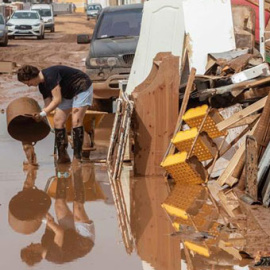 Una mujer vierte lodo en Cartagena, afectada por las inundaciones provocadas por las lluvias caídas en Murcia. / EFE