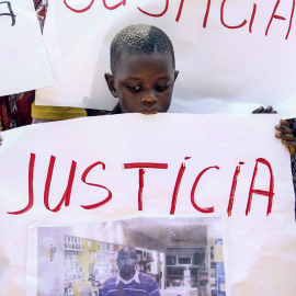Inmigrantes senegaleses muestran pancartas contra la los Mossos D'esquadra en la manifestació en Salou para protestar por la muerte de un compatriota en una operación contra el 'top manta'. AFP PHOTO / QUIQUE GARCIA