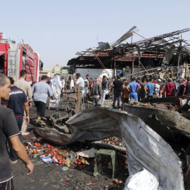Varias personas caminan por el lugar donde se ha producido un atentado en un mercado en Bagdad (Irak) reivindicado por el Estado Islámico. EFE/Ahmed Ali