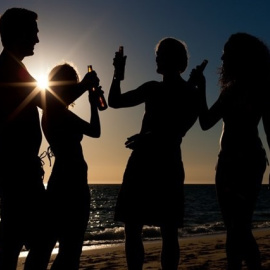 Jóvenes consumen alcohol en la playa al atardecer.- E.P.