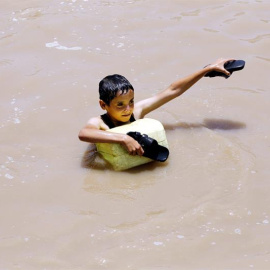 Un niño camina con el agua hasta los hombros por una calle inundada en Saná (Yemen). Al menos cinco personas han muerto a causas de las lluvias torrenciales que han sufrido varias regiones del país. EFE/Yahya Arhab