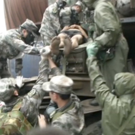 Soldados llevan a un superviviente en el almacén portuario de Tianjin (China)./ REUTERS