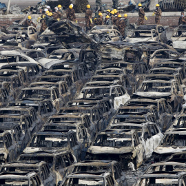 Los equipos de rescate se colocan cerca de los vehículos dañados cerca del lugar de las explosiones de la semana pasada en el nuevo distrito de Binhai en Tianjin, China. REUTERS