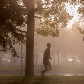 Un hombre corre entre la neblina por la mañana en Vitoria.
