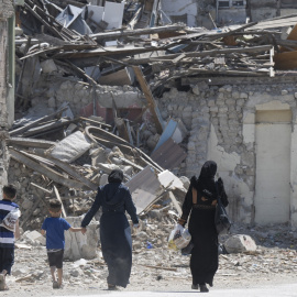 Imagen de archivo de un dos mujeres y dos niños caminando entre los escombros de uno de los 6.000 edificios que derrumbaron los terremotos de Turquía en febrero de 2023.