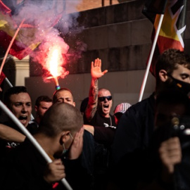 Jóvenes neonazis con bengalas levantan el brazo durante una manifestación neonazi para celebrar el día de la Hispanidad, a 12 de octubre de 2021, en Barcelona.