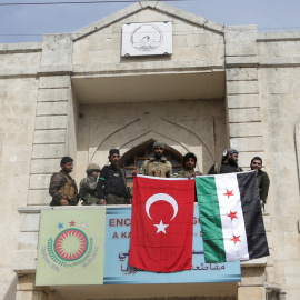 Los miembros de las fuerzas turcas y del Ejército Sirio Libre posan con sus banderas mientras se despliegan en Afrin, Siria.REUTERS