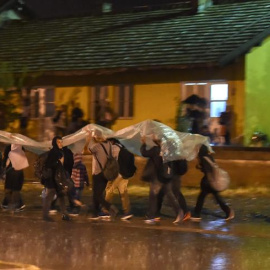 Los migrantes se protegen de la lluvia con un plástico mientras caminan para coger el tren en dirección a la frontera con Serbia, después de recibir el permiso para cruzar en Macedonia en la estación de tren en Gevgelija.-EFE