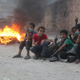 Niños sirios se refugian de los ataques aéreos tras unos neumáticos en llamas para que el humo reduzca la visibilidad y sea más complicado bombardearlos/Alepo Media Center y Syria Campaign