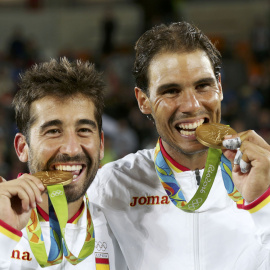Los tenistas españoles Rafael Nadal y Marc López muerden la medalla de oro ganada hoy en la final de tenis de dobles masculino en los Juegos Olímpicos de Brasil 2016. REUTERS/Kevin Lamarque