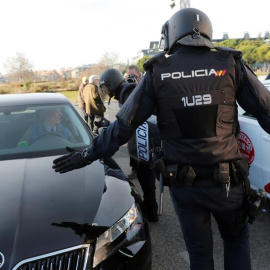Efectivos de la Policía Nacional entre un vehículo de licencia VTC y un taxi a las puertas del recinto ferial de Ifema. EFE/Chema Moya