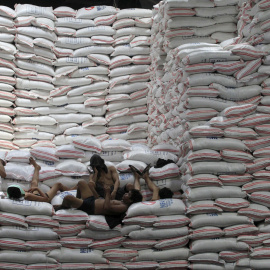 Trabajadores descansan encima de sacos de arroz apilados dentro de un almacén de la Autoridad Nacional de Alimentos en la ciudad de Taguig, al sur de Manila, 25 de agosto de 2015. REUTERS/Romeo Ranoco